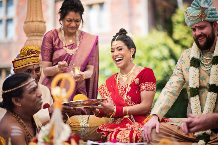 Bride and groom laugh during the Hindu ceremony at North Mymms Park, candidly photographed by Blooming Photography.