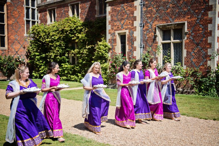 Bridesmaids in procession with gifts, during Hindu ceremony at North Mymms Park, candidly photographed by Blooming Photography.
