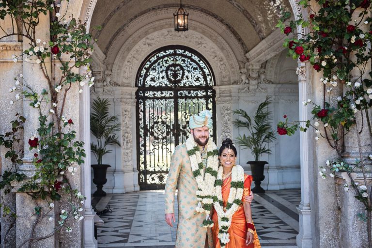Bride and Groom stand under the arches at North Mymms Park, candidly photographed by Blooming Photography.