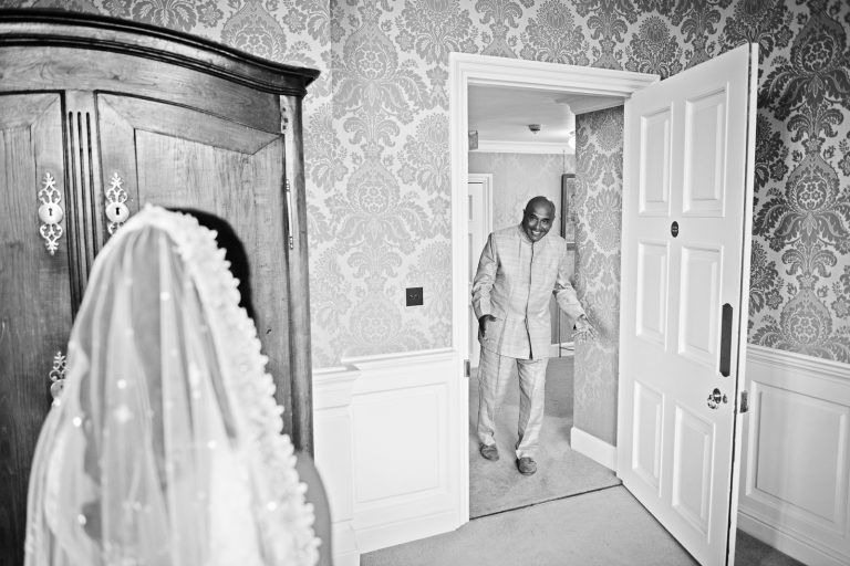 Father of the bride in the doorway seeing his daughter in her wedding dress for the first time. Taken at North Mymms Park, candidly photographed by Blooming Photography.