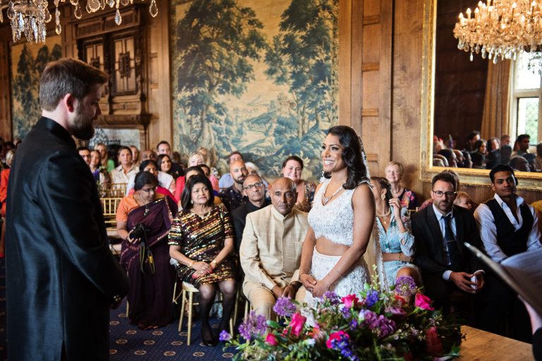A bride and groom stand facing each other in the Great Hall at North Mymms Park, candidly photographed by Blooming Photography.
