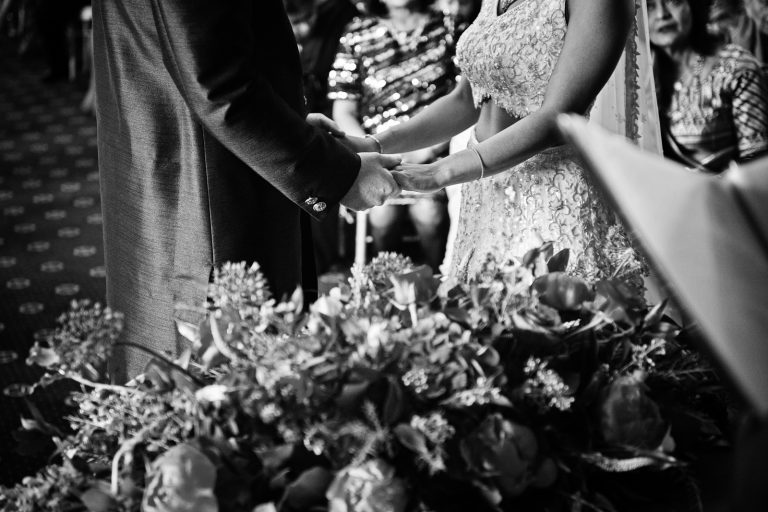 Close up photograph of bride and grooms hands as they hold each other during the wedding ceremony. Black and white image. Photographed at North Mymms Park, by Blooming Photography.
