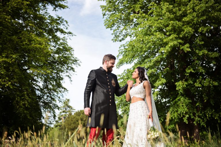 A bride and groom hold an emotional handshake. Photographed at North Mymms Park, by Blooming Photography.