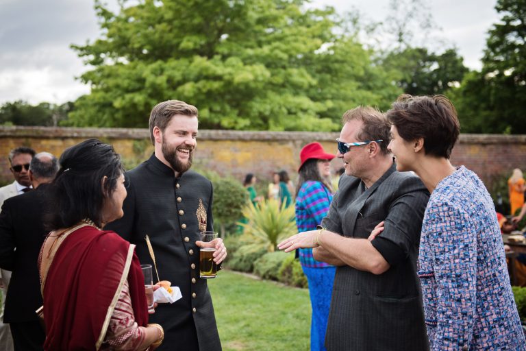 Guests chatting to the bride and groom. Photographed at North Mymms Park, by Blooming Photography.