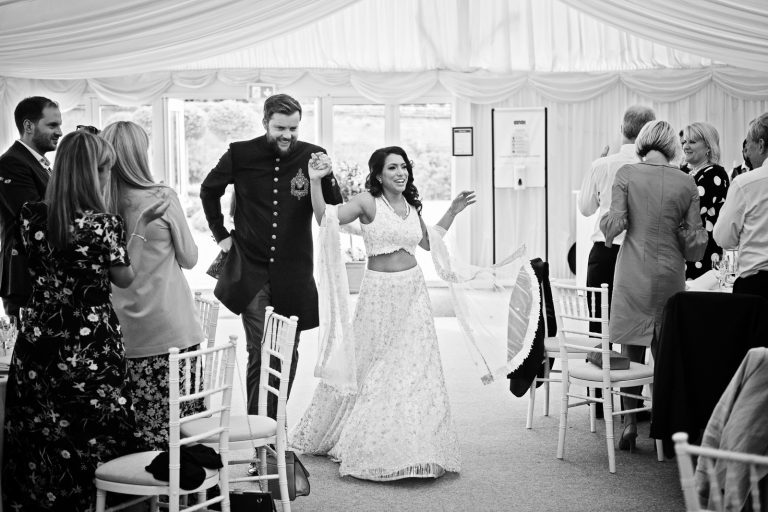 Bride and groom enter the marquee. Black & white photo. Photographed at North Mymms Park, by Blooming Photography.