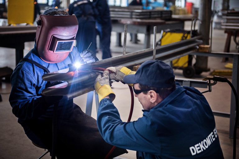 Two workers welding an expansion joint in a manufacturing factory in Romania.