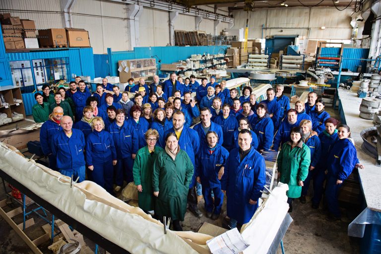 Large group shot of 50 staff in a engineering factory in Romania. Everyone smiling.