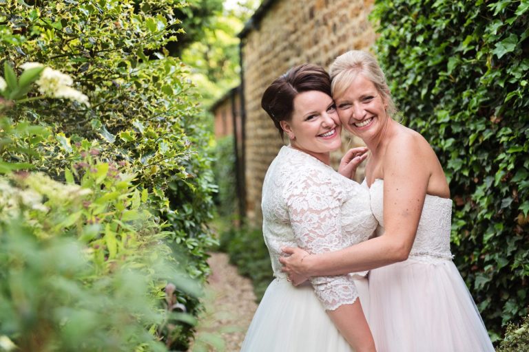 Bride and bride smile at the camera.