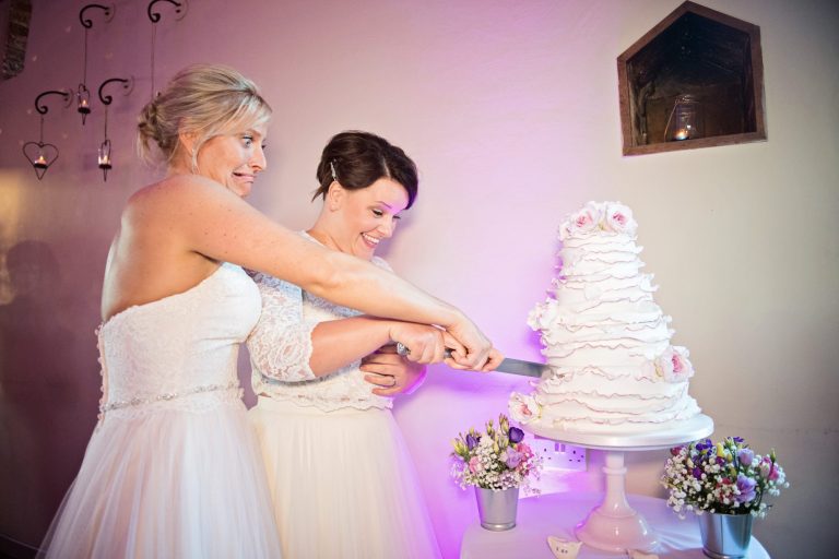 Fun photo of Bride and bride cutting their wedding cake.