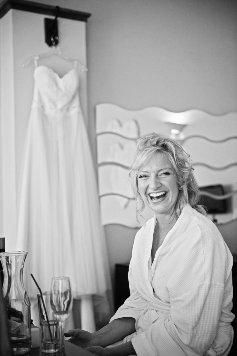 B&W portrait photo of bride naturally laughing at the camera.
