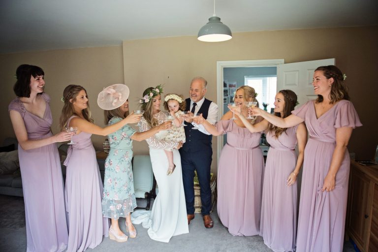 Bride and her father and daughter and all bridesmaids, give each other a cheers as they are ready on time!