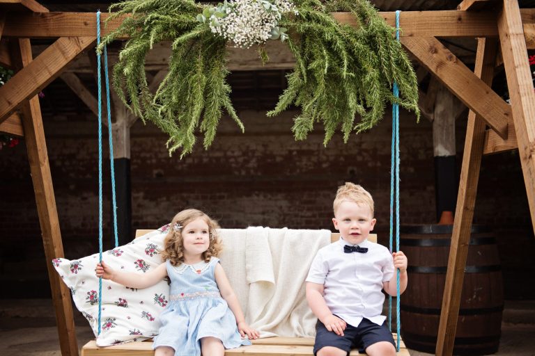 Candid wedding photo of two children sitting on a swing at Overbarn, Gloucester