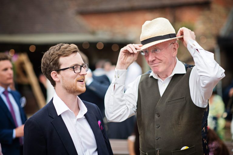 Candid wedding photo of guest trying on a hat at Overbarn, Gloucester