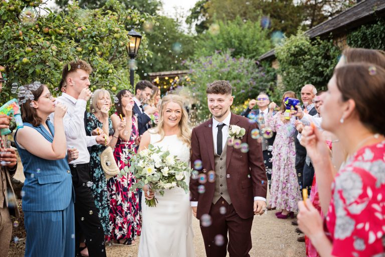 Bride & Groom walking down a bubble isle that is being created by their friends and family