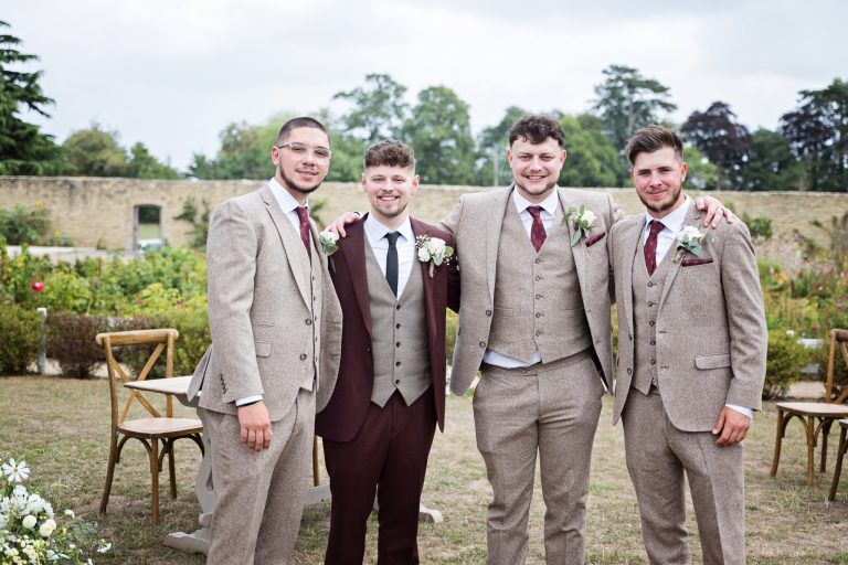 the groom and his groomsmen face on to the camera smiling