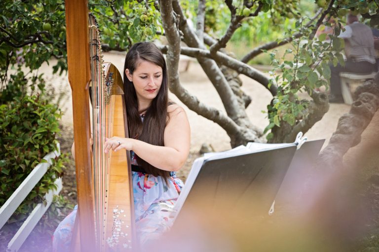 a harpest playing the harp in a garden