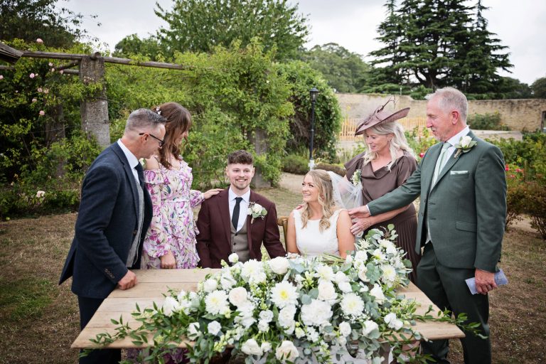 Bride and groom being surrounded by their parents after they have just signed the wedding register