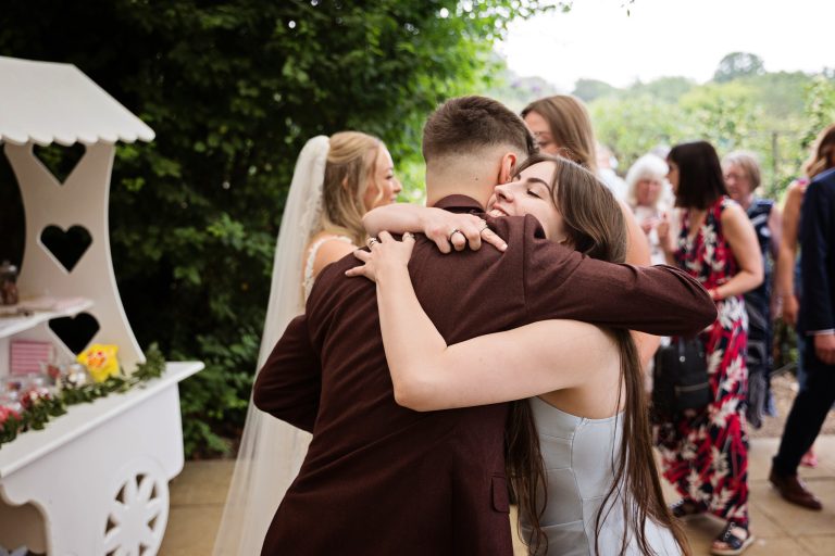 image of a groom being hugged by a wedding guest