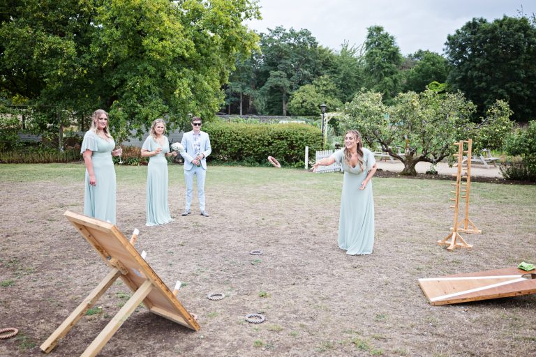 a bridesmaid throwing a hoop at a garden game. Wedding guest watching