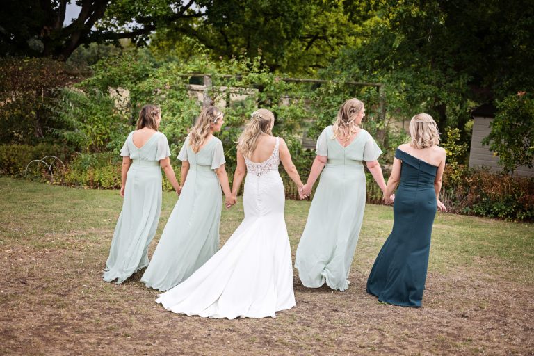 bride and bridesmaids walking away from the camera hand in hand