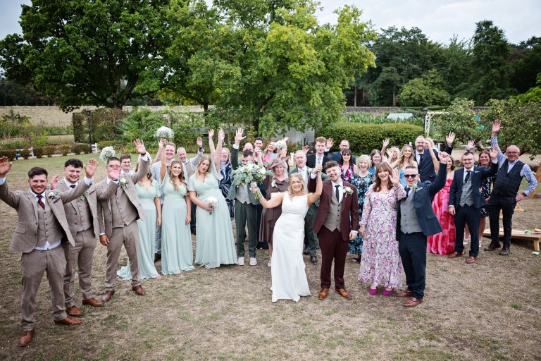A Group photo of everyone with their hands in the air and smiling at the camera