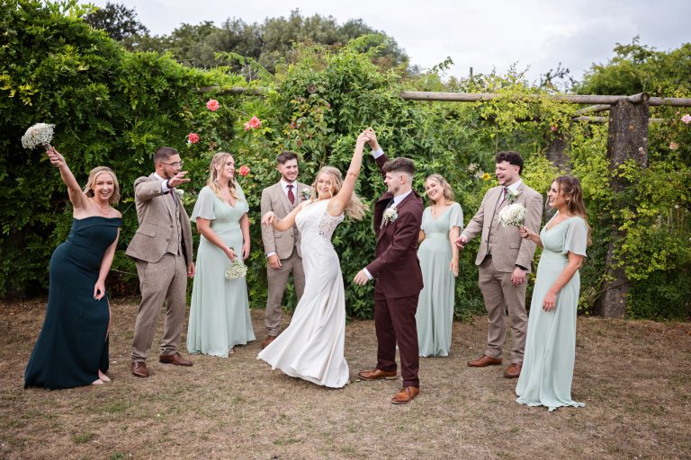 bride & groom do a pretend first dance surrounded by their bridal party in a gorgeous garden