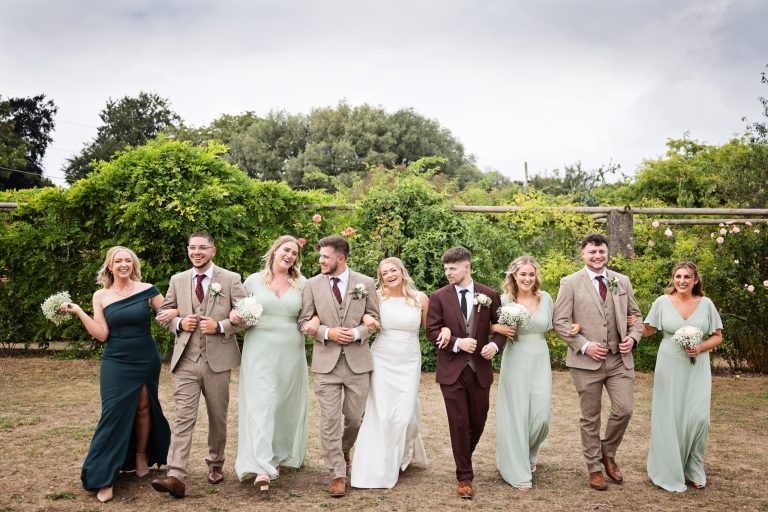 fun image of the bridal party walking together with their arms linked together.