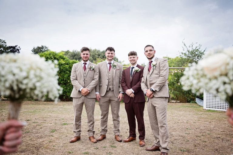 grooms men stand with the bridesmaids flowers on either side of the photo.