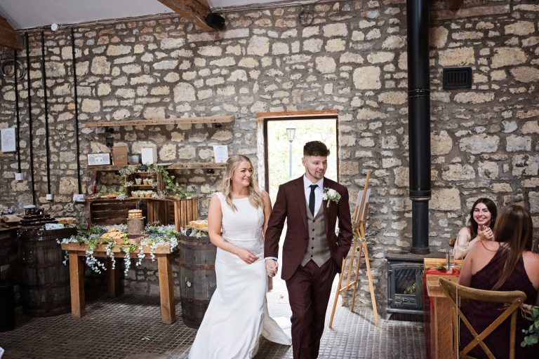 bride & groom enter the wedding breakfast cheered on by a guest