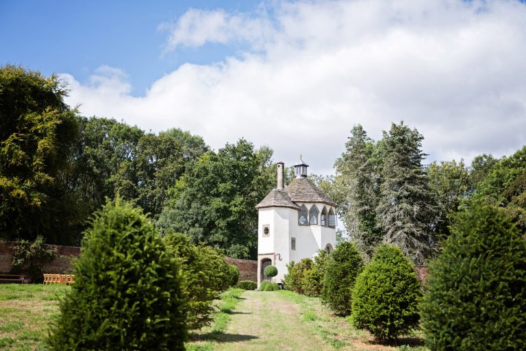 Outside scene of Homme House castle folly, with chairs out and surrounded by green trees