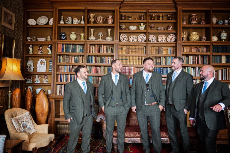 Photo of groomsmen standing, smiling at each other in a Georgian library.