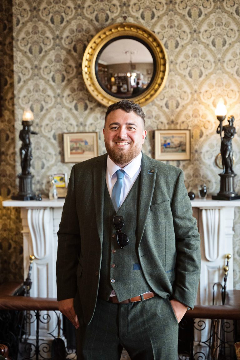Photo of groom standing in front of a Georgian fireplace