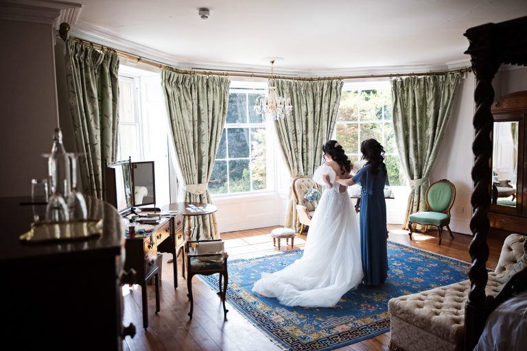 a bride bride getting in her wedding dress - in front of a gorgeous bay window