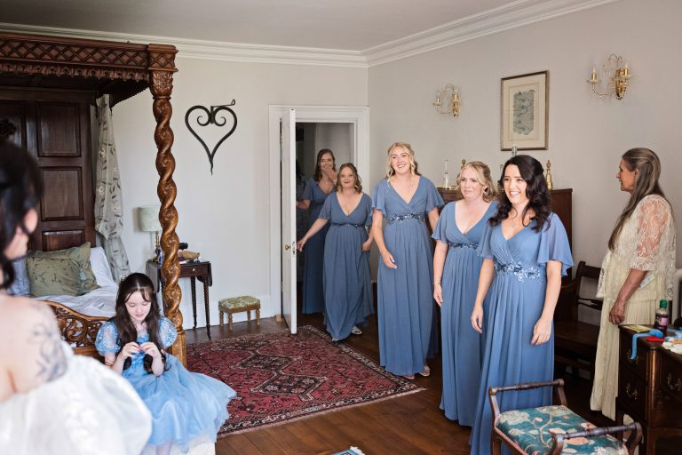 Bridesmaid and flower girls emotionally look at the bride in her wedding dress