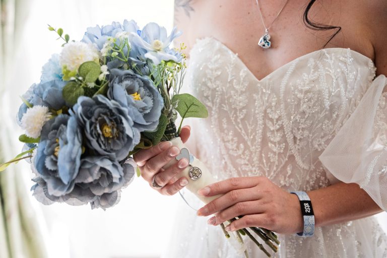 A bride holds her bouquet with sentimental things attached to the bouquet
