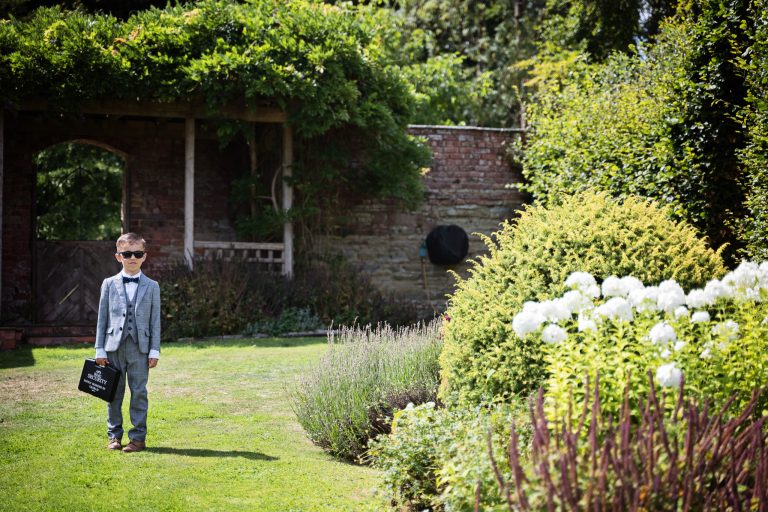 a ring bearer waits for the approaching bridal party