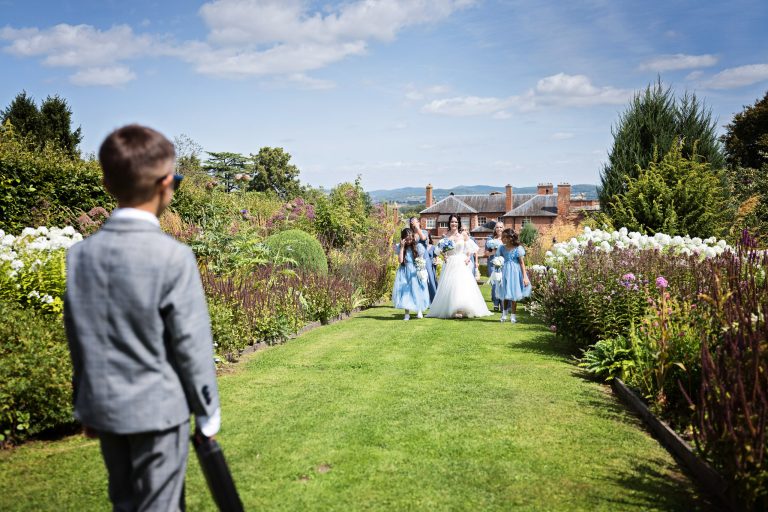a ring bearer waits for the approaching bridal party