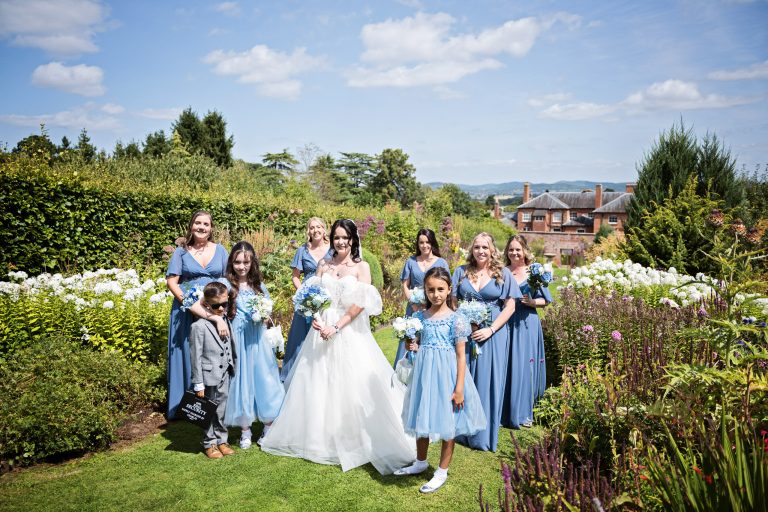 The bride and bridal party await in a cottage garden before they walk down the isle