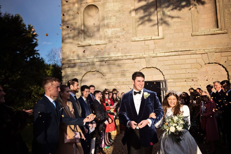 Gorgeous photo of bride and groom being showered with confetti by their wedding guests outside the chapel at Compton Verney