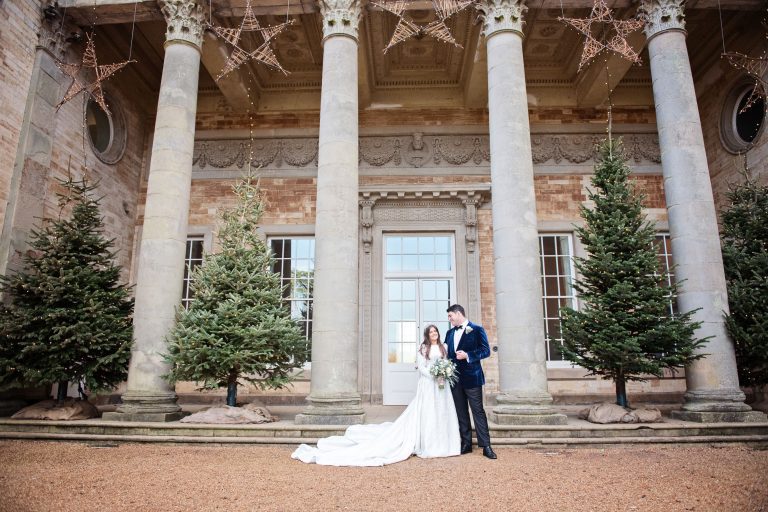 Exterior shot of Bride and groom standing in front of the tall pillars at Compton Verney.