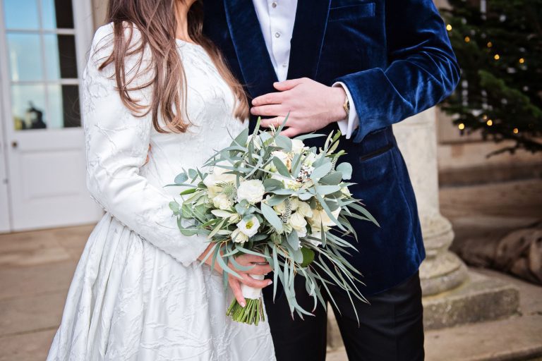 Close up photo of the wedding bouquet with the Bride and groom behind them.
