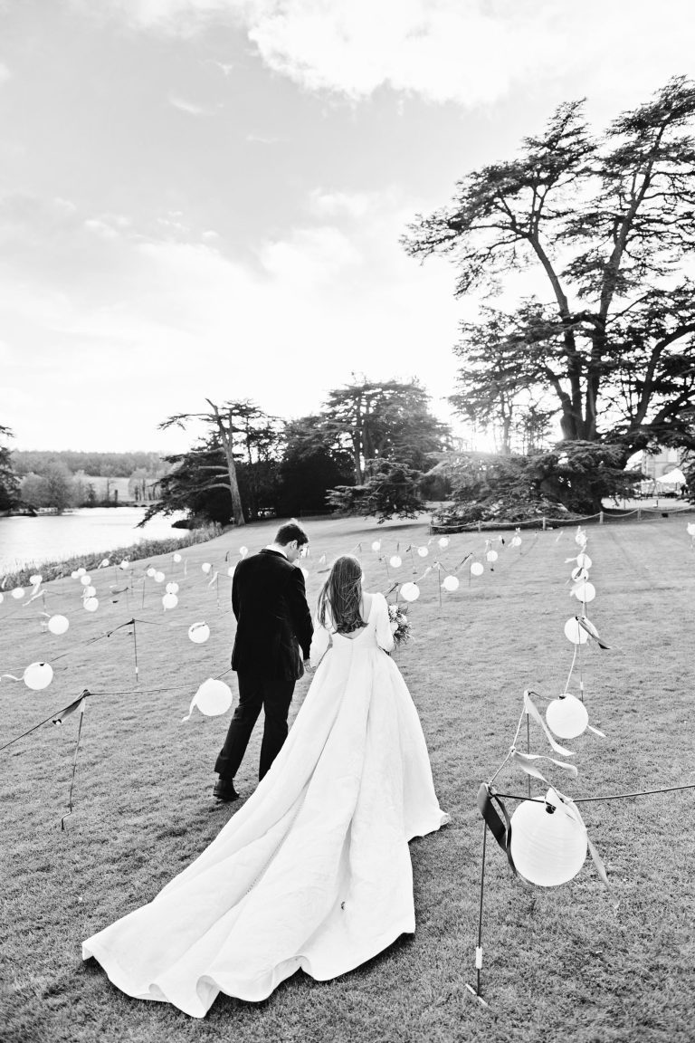 B&W portrait photo of a bride and groom walking in the art installation of Compton Verney.