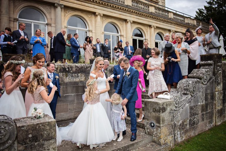 Candid storytelling moment of wedding guests on the terrace at Cowley Manor.