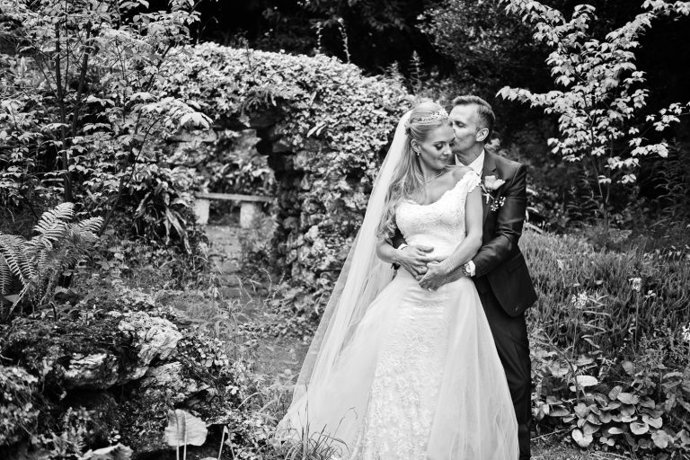 B&W timeless photo of a bride and groom grabbing a moment together in the gardens.
