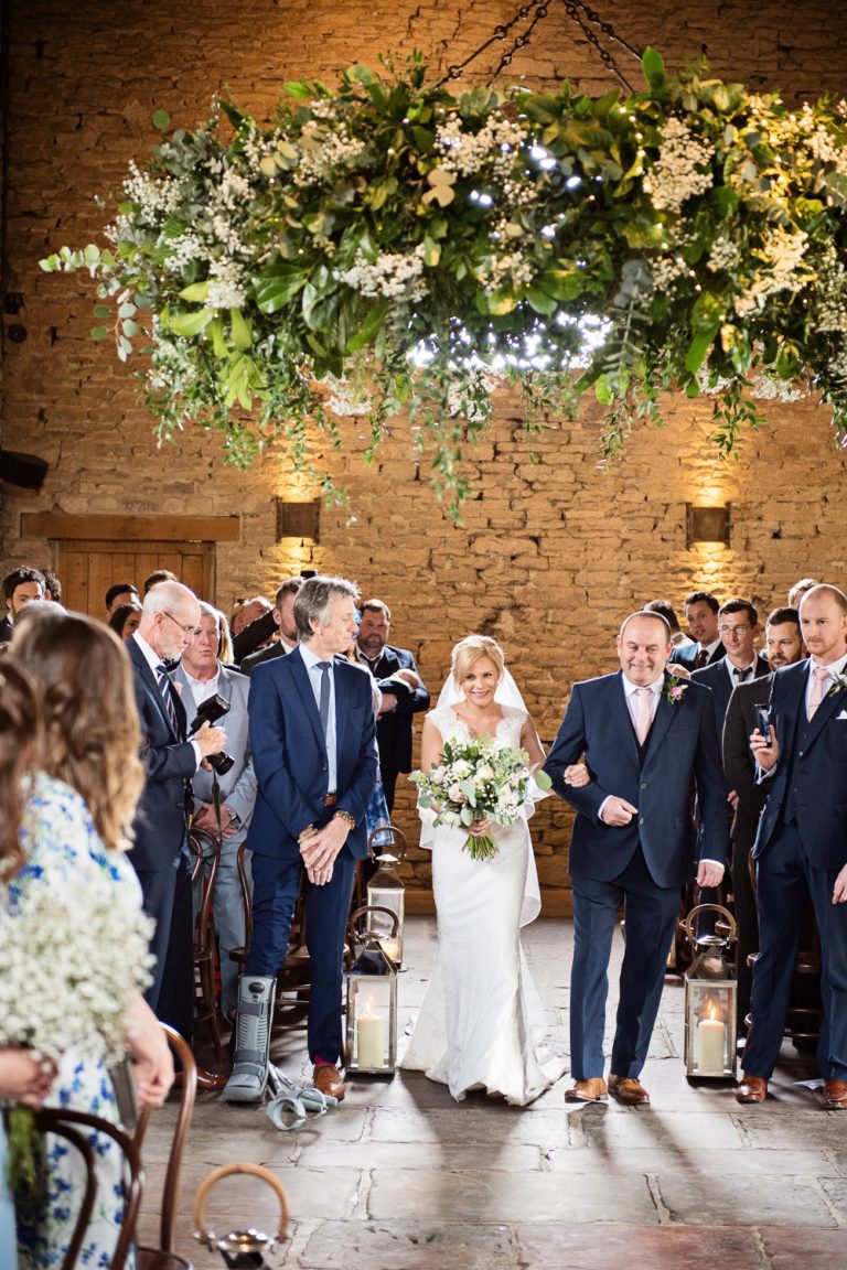 Story telling portrait photo of the bride and her father walking down the wedding isle at Cripps Barn