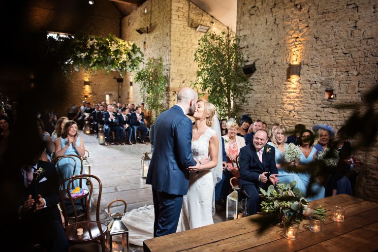 Bride and groom kiss as they are announced husband and wife at their wedding at the Cotswold wedding venue, Cripps Barn.