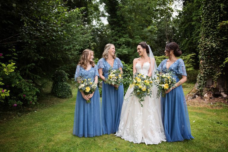 Bride and bridesmaids standing in the Cripps Barn gardens.