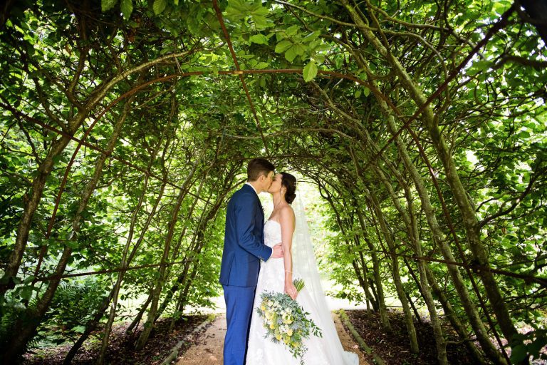 Bride and groom kiss in archway.