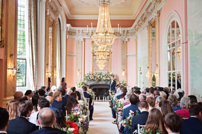 A groom stands at the front of the isle, waiting for his bride.