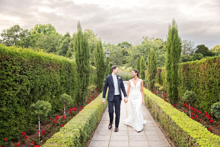 Bride and groom hold hands as they walk down the path at Danesfield House.
